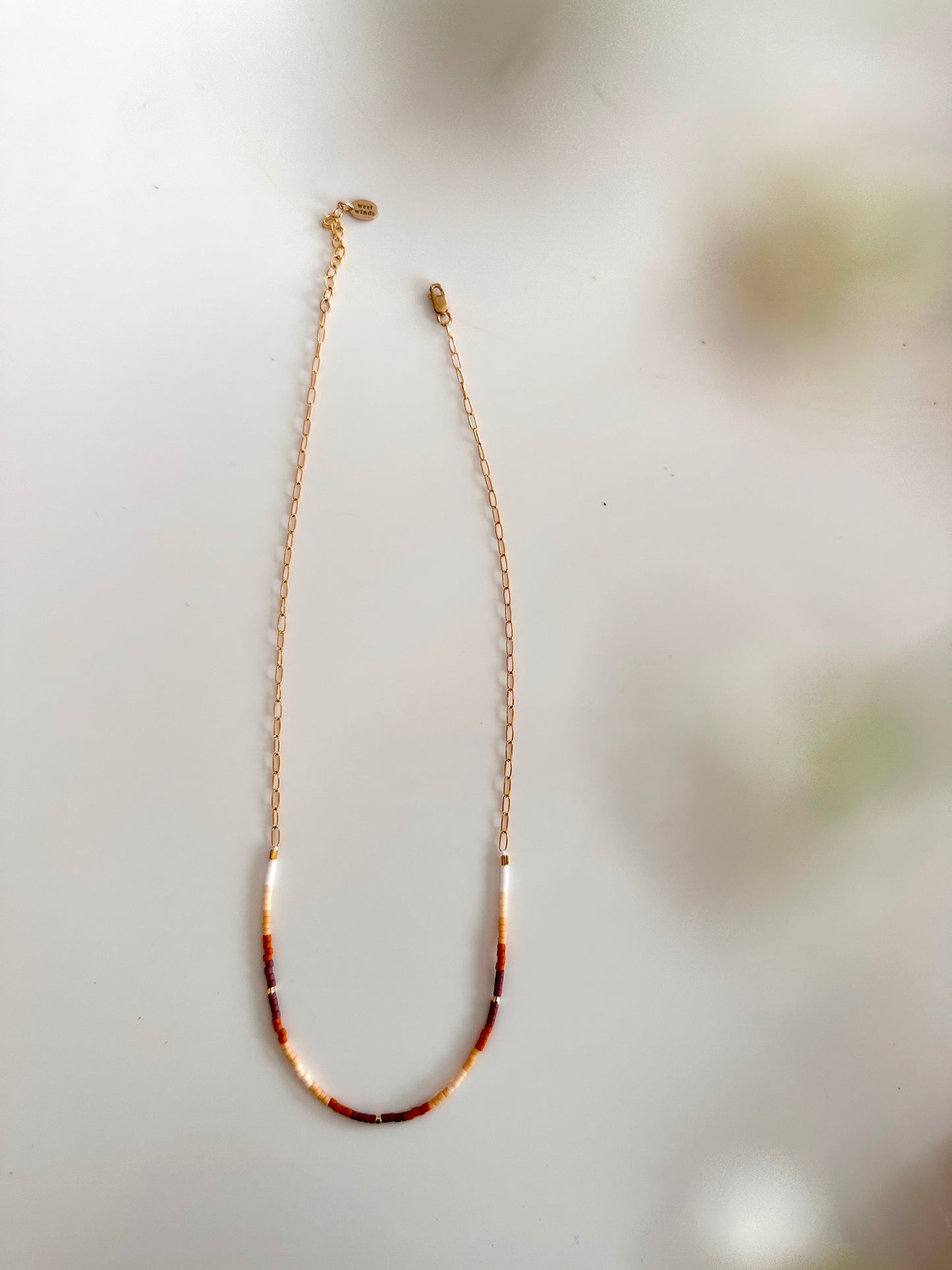Gold necklace with tortoiseshell accents on a light background